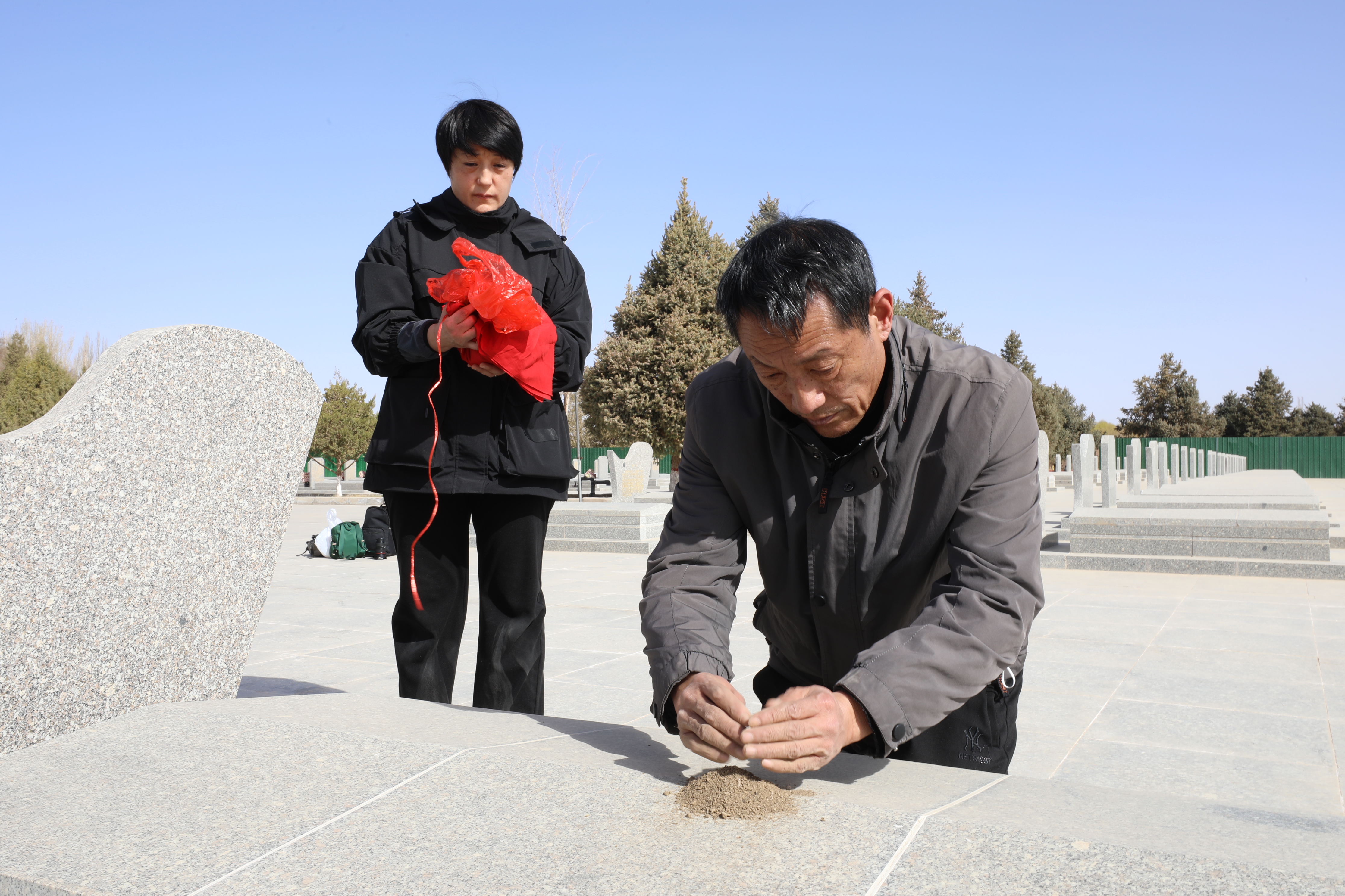 烈士侄儿董淑波、侄女董淑萍将从家乡赣榆带来的故土小心翼翼地洒在叔叔的墓地上