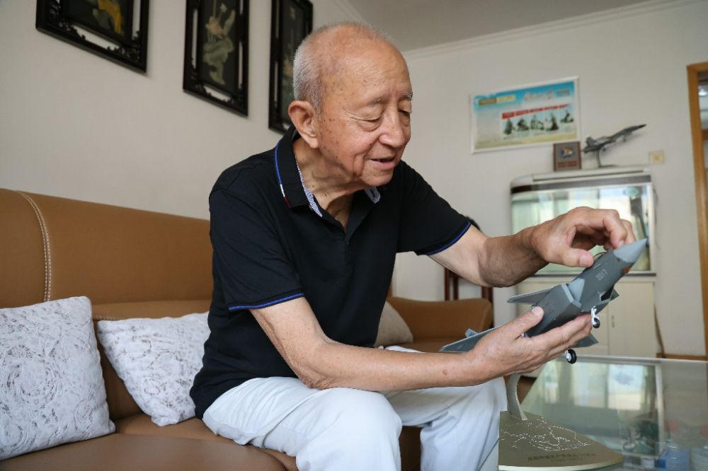 ↑2023年7月24日,新中国第一代飞行员陶伟在家中擦拭歼-20飞机模型。新华社发(张瑞 摄)